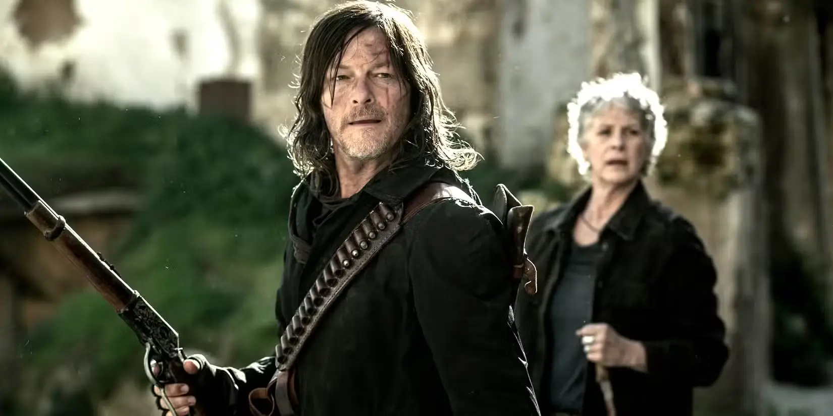 norman-reedus-daryl-con-un-fucile-in-mano-e-melissa-mcbride-s-carol-sullo-sfondo-in-the-walking-dead-daryl-dixon-stagione-3