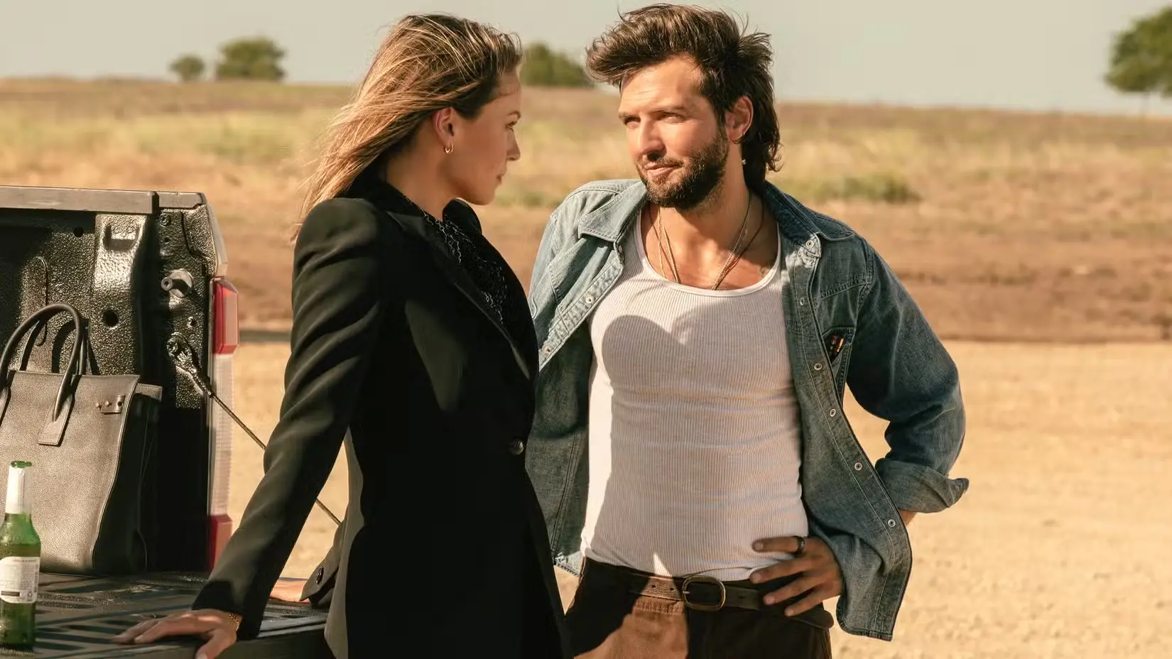 kayla-wallace-s-rebecca-and-guy-burnet-s-charlie-leaning-against-a-truck-flirting-with-each-other-in-landman-season-2